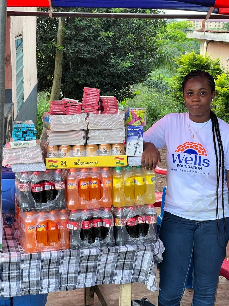 Volunteer with donated drinks and supplies at a Wells Foundation community event in Ghana