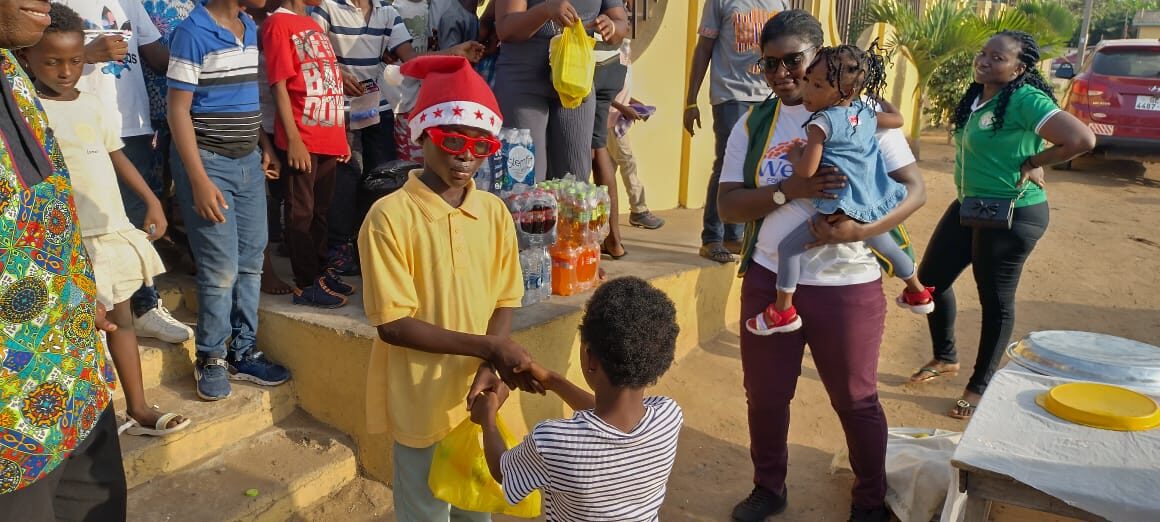 A volunteer handing a gift to a child at a Wells Foundation event